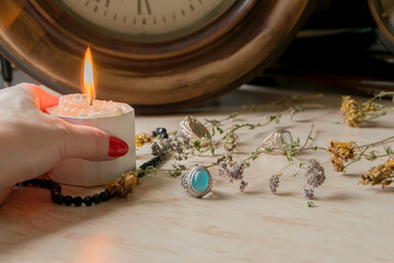 female hand holds a burning candle on a light natural background. pagan wiccan, slavic traditions. Witchcraft, esoteric spiritual ritual for mabon, halloween, samhain