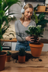 Wall Mural - Young woman potting a plant at home