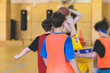 Junior teenage school team of kids children play basketball, players in the hall indoor venue court, sports team during the game, playing indoor match game on arena stadium on a wooden parquet floor
