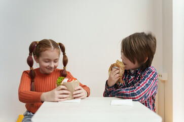 Two little kids eating gyros and souvlaki in Greek restaurant. Elementary age boy and girl enjoying lunch in fast food cafe