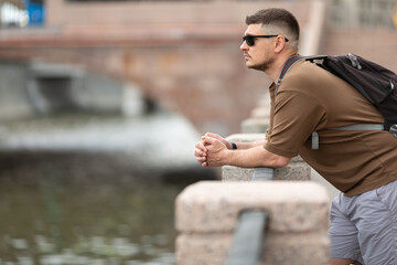 The man leans on the embankment railing and looks thoughtfully