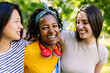 © Xavier Lorenzo - Three joyful multiracial young teenage girls having fun outdoors. United millennial women laughing enjoying time together. Latin american pretty female smiling at camera standing with friends.