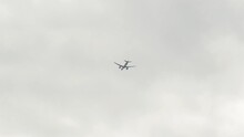 White Passenger Plane Flies In Cloudy Sky. Unmarked Aircraft In Sky, Viewed From Bottom Up.