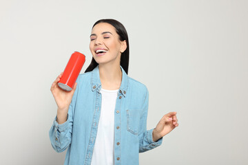 Sticker - Beautiful happy woman holding red beverage can on light grey background. Space for text