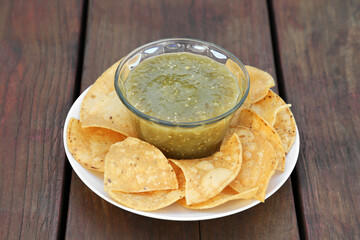 Tasty salsa sauce and tortilla chips on wooden table, closeup