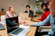 © dikushin - Successful young startup business team of diverse young businesspeople working sitting at table with laptop in modern boardroom. Focused multiethnic colleagues brainstorm discuss report.