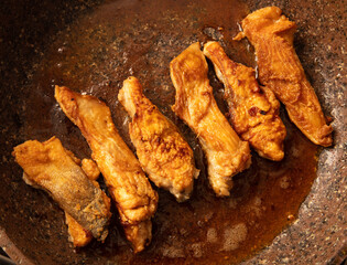 Wall Mural - The fish is fried in a frying pan in oil. Close-up.