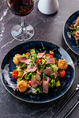 Sticker - salad with beef, vegetables, herbs, sauce in a plate on the tabl