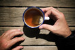 © Cavan Images - Cropped hands of man holding tea in cup on wooden table