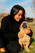 © mariiya - a beautiful dark-haired girl, in a black sweater spends time with a dog, a homeless dog,friends lie on the grass in the yard, hugging, taking pictures on the phone. the girl cares about a homeless dog