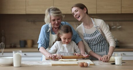 Wall Mural - Happy mom and grandma teaching kid to bake, rolling dough for pastry together. Girl and women of three family generations cooking homemade bakery food, having fun, laughing at messy kitchen table