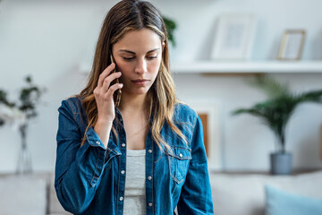 Beautiful young woman talking on the phone at home.