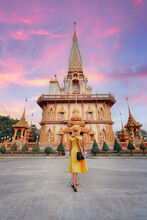 Travel By Asia. Young Woman In Hat And Yellow Dress Walking Near The Chalong Buddhist Temple On Phuket Island In Thailand.