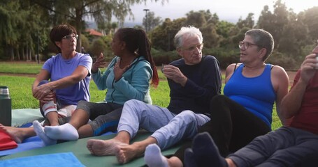 Wall Mural - Multiracial senior people having fun drinking hot tea after workout exercises outdoor with city park in background - Healthy lifestyle and joyful elderly lifestyle concept