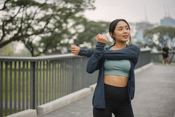 Asian happy woman exercise in park on morning. Healthy female wearing sportswear and stretching body before running in outdoors. wellness lifestyle, outside activities.