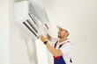 © Studio Romantic - Portrait of smiling professional technician worker in uniform and white cap is changing filter in air conditioner indoors. Repair and maintenance of household appliances concept.