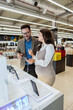 © Dusko - Beautiful and happy middle age couple buying consumer tech products in modern home appliances store. They are choosing smart phone or digital tablet. People and consumerism concept.
