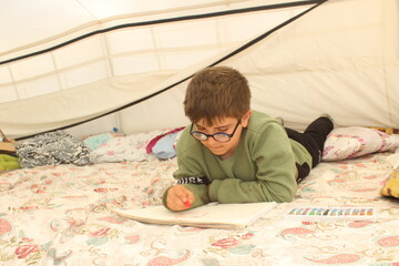 Earthquake survivor boy drawing in tent.