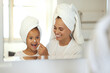 © Kirsten D/peopleimages.com - Smiling, joyful and excited little girl in spa with her mother. Mom and daughter self care day, putting on creams and taking care of skin. Parenthood, bonding with child, young female growing up