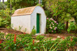 Kleine weise Hütte mit grüner Tür in einem Blumengarten
