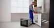 © Andrey Popov - Young Repairman Installing Induction Cooker