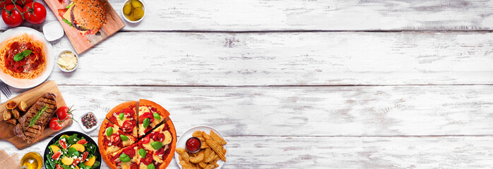 Wall Mural - Corner border of a variety of delicious foods. Above view on a white wood banner background. Copy space.