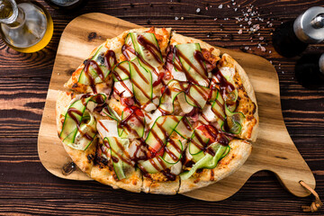 Canvas Print - Italian food pizza with chicken, bacon, cucumbers, tomatoes and barbecue sauce on a thick dough.