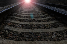 Railway Rails From A Low Shooting Point Go Into A Distant Perspective, From Which A Bright Light Is Directed Towards The Viewer