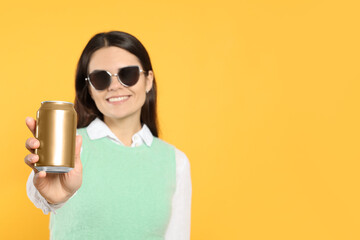 Poster - Beautiful happy woman holding beverage can on yellow background. Space for text