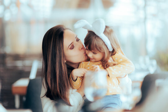 mother kissing her child wearing bunny ears on easter. happy mom and her daughter having fun bonding