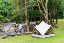 Nature Camping White Tent On Green Grass Meadow Or Lawn And Family Relax Camp In Tree Forest Or Natural Garden For Holiday At Phalad Waterfall In Lan Sang National Park Campground At Tak And Thailand
