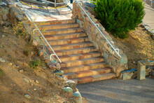 Cement Stone And Rock Stairs Steps With Metal Hand Rail And Asphalt With Dry Grass And Shrub Nearby