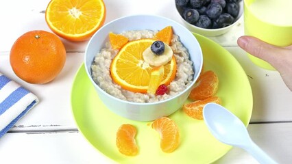 Wall Mural - Children's breakfast oatmeal with fruits and nuts. Fox muzzle made of oranges. Healthy food for kids.