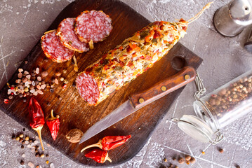 Canvas Print - Salami sausage with slices on wooden board on a table