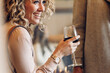 © Cavan Images - Cheerful businesswoman holding wineglass while looking away in hotel