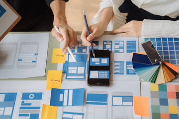 UI developer and ui designer brainstorming about mobile app interface wireframe design with customer breif and color code at office.