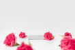 Cosmetics product presentation scene made with pumice stone pedestal and pink roses on white background. Studio photography.