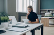© gstockstudio - Serious young businesswoman using digital tablet while working in the office