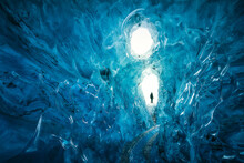 Man Ice Climber Exploring A Frozen Paradise Inside A Blue Ice Cave In Vatnajokull Glacier, Golden Circle Route, Iceland