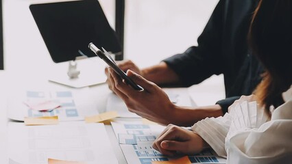 Close up ux developer and ui designer brainstorming about mobile app interface wireframe design on table with customer breif and color code at modern office.Creative digital development agency