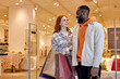 © Roman - Happy Loving Family at mall . side view portrait of smiling african american man and ginger woman looking at each other, carrying shopping bags, girl thanks her boyfriend for presents, gifts