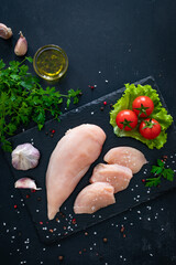 Wall Mural - Fresh raw chicken fillet on cutting board with spices on black background
