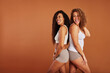 © Flamingo Images - Diverse women in underwear standing back to back on an orange background