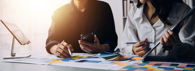 Close up ux developer and ui designer brainstorming about mobile app interface wireframe design on table with customer breif and color code at modern office.Creative digital development agency