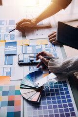 Close up ux developer and ui designer brainstorming about mobile app interface wireframe design on table with customer breif and color code at modern office.Creative digital development agency