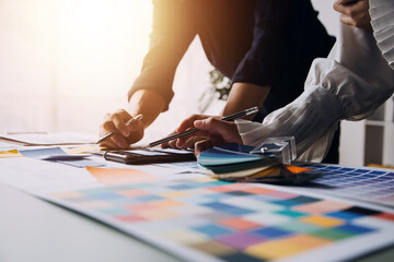 Close up ux developer and ui designer brainstorming about mobile app interface wireframe design on table with customer breif and color code at modern office.Creative digital development agency