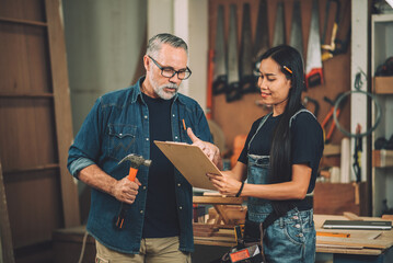 Wall Mural - Professional carpenter with wife small business wood shop owner working together with teamwork.