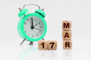 On a white background, a green alarm clock and a calendar with the inscription - March 17