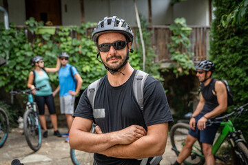 man caucasian male ride electric bicycle e-bike with friends in summer