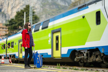 Young Woman On A Railway Station. A Girl Waiting For A Train On A Platform. Female Tourist With A Luggage Suitcase Ready To Travel.
